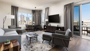 A modern living room with a sofa, armchairs, a coffee table, and a TV. There is a balcony with a view of the city. - DoubleTree by Hilton Tucson Downtown Convention Center (Tucson)