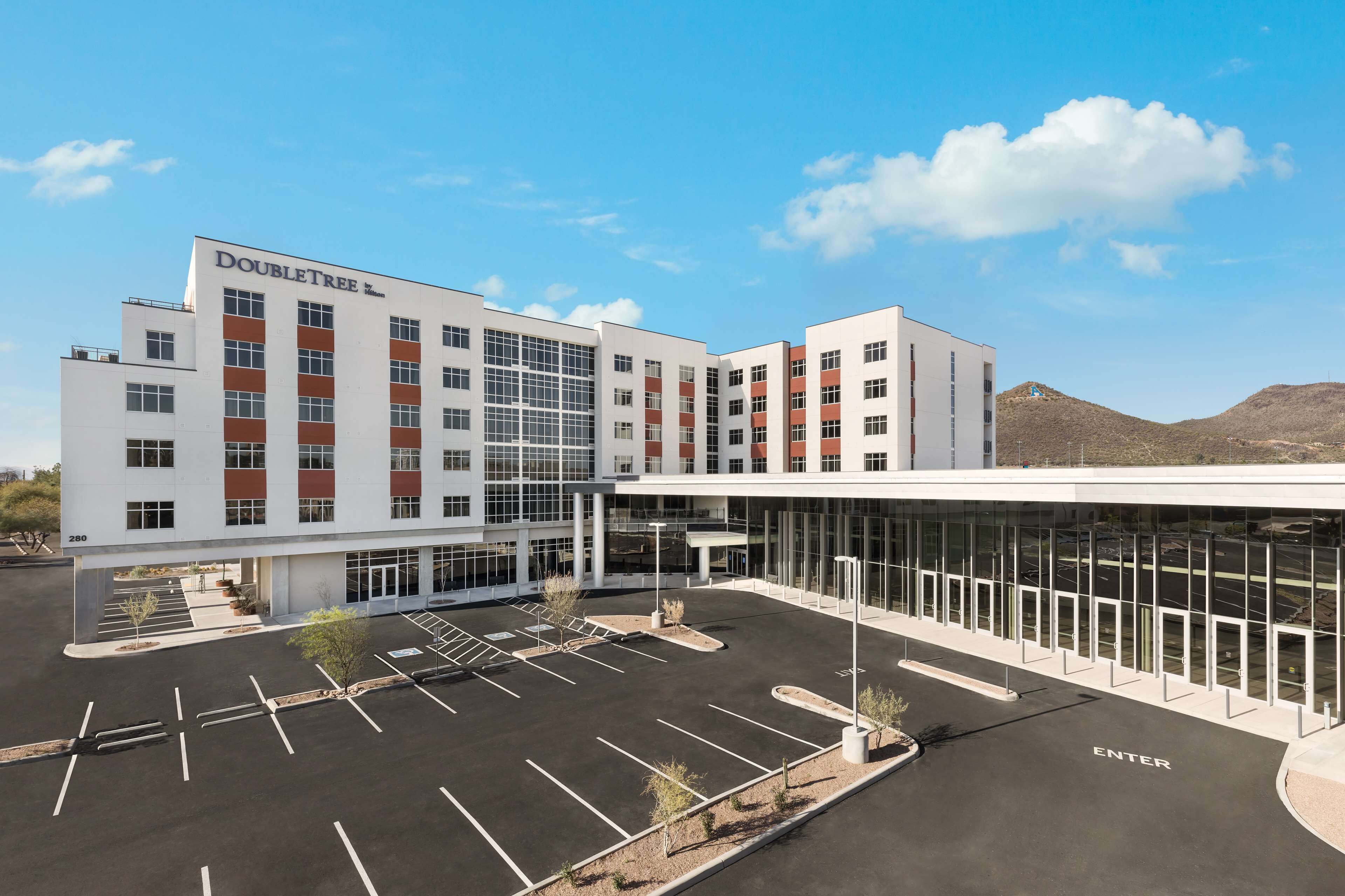 Un hotel moderno con un ampio parcheggio e un ingresso in vetro.