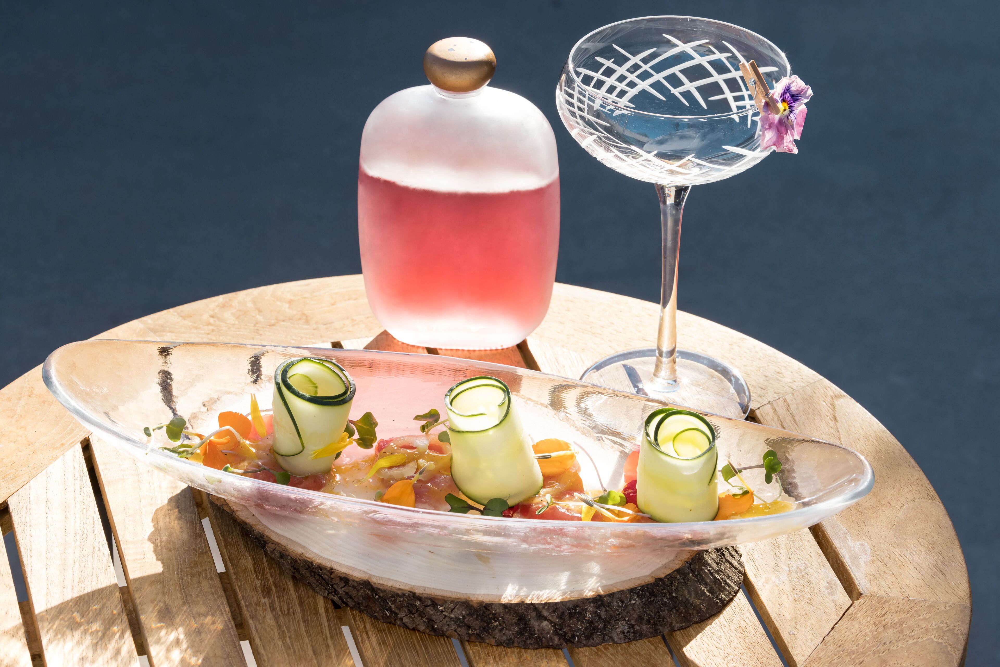 Un recipiente de vidrio con comida y bebidas sobre una mesa de madera.