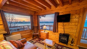 Een gezellig chalet met houten inrichting, een bank, een tafel, een stoel, een televisie en een open haard.