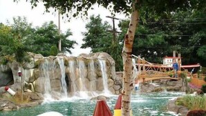 A water park with a waterfall, a wooden bridge, and a small boat. - Waterfront on the Cove, NEW Kitchen and Central AC (Orleans)
