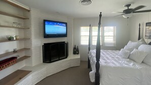A bedroom with a four-poster bed, a television mounted on a white brick wall, and a ceiling fan. - 12th Green at Duncan Golf Club and Tennis Club (Duncan)