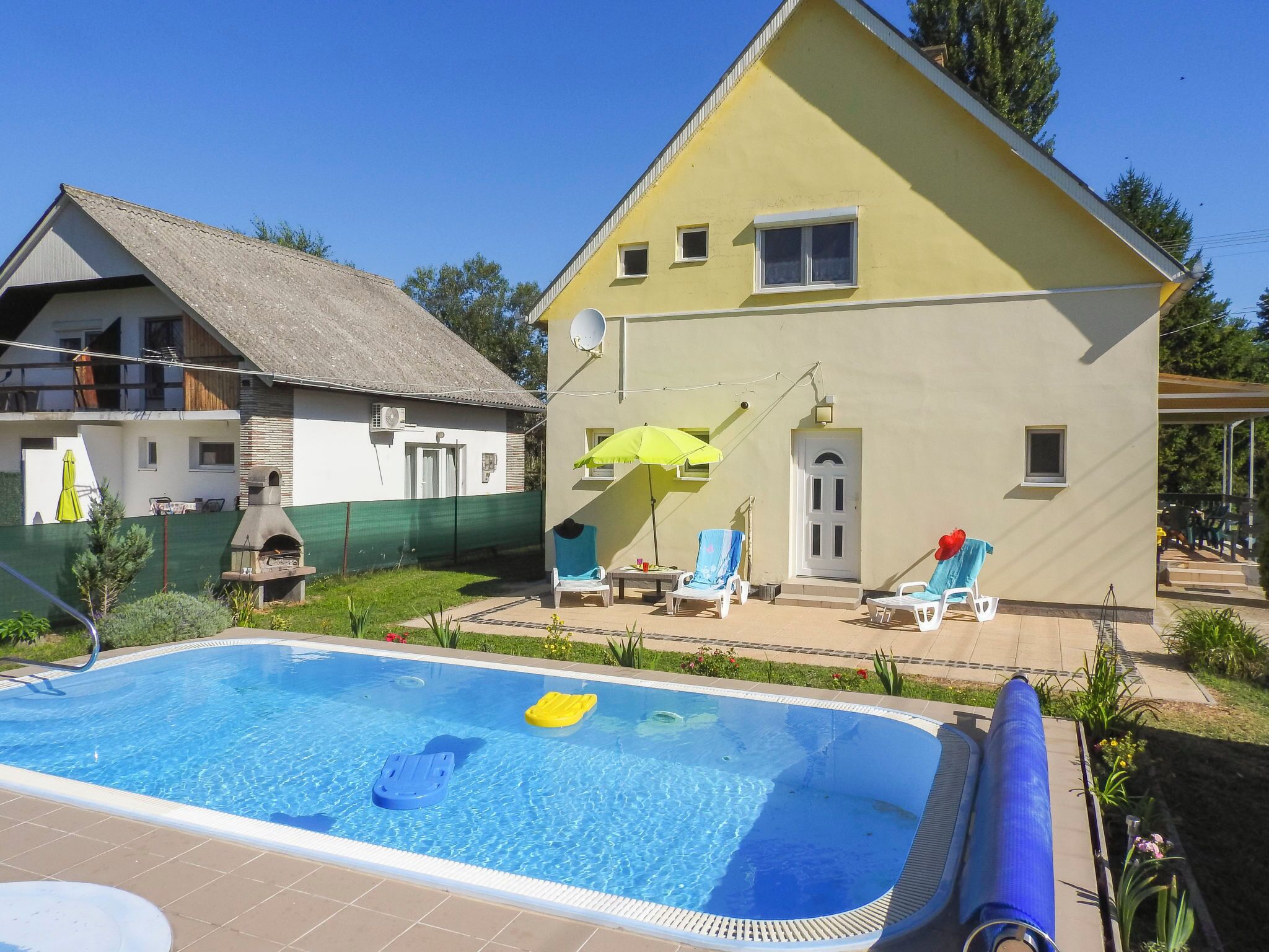 A swimming pool with lounge chairs and a barbecue grill.