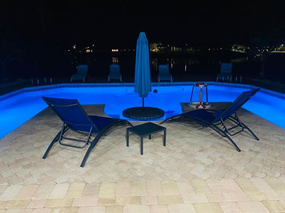 Ein Poolbereich im Freien mit Liegestühlen und einem Tisch, umgeben von einer gefliesten Terrasse.