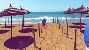 Een strand met rijen rieten parasols en touwen.
