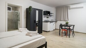 Ein modernes Schlafzimmer mit Bett, Dusche, Küchenzeile und Essbereich.