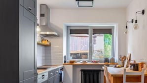 Een moderne keuken met grijze kastjes, een houten aanrechtblad en een raam met uitzicht op een tuin.