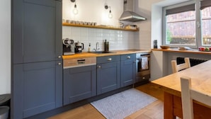 Een moderne keuken met grijze kastjes, een houten aanrechtblad, een ingebouwde oven en een raam met uitzicht.