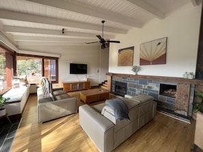 Amplia sala de estar con chimenea, televisor y ventilador de techo.