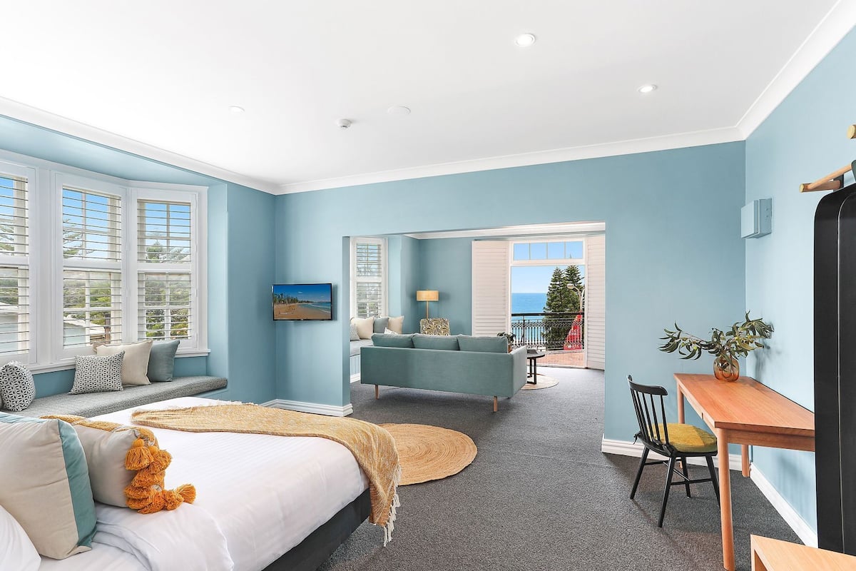 Une chambre avec un lit, un canapé, une table à manger et une vue sur la mer.