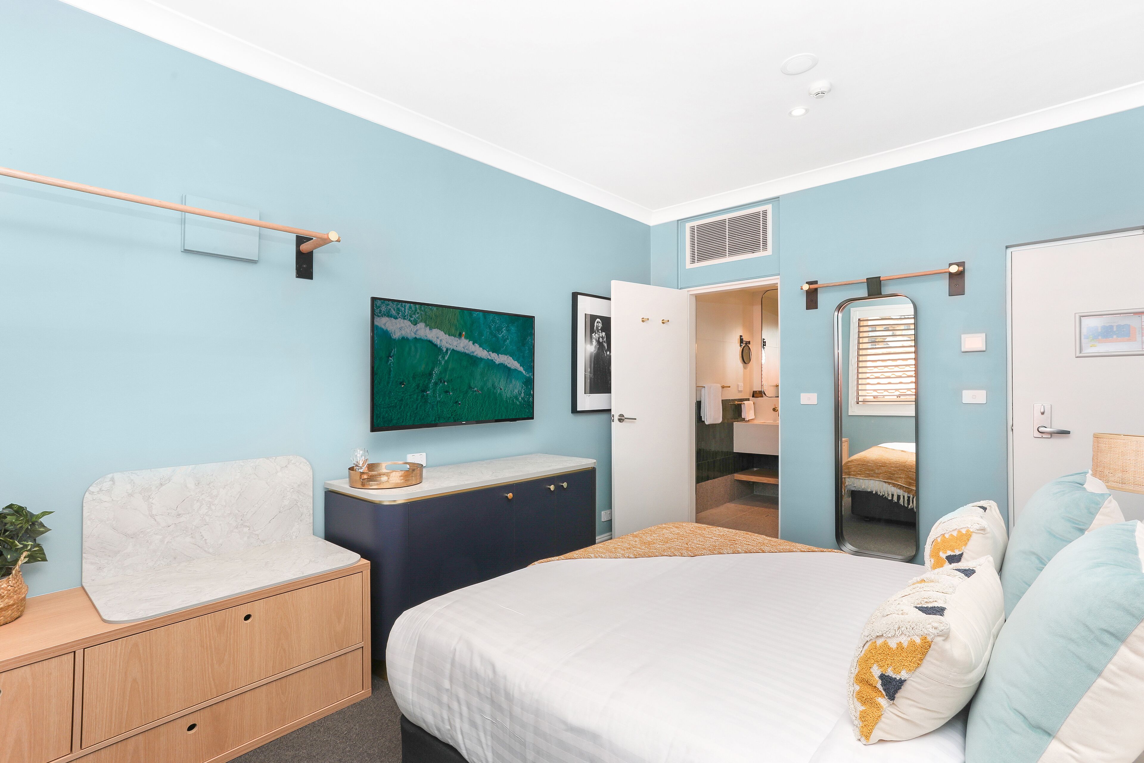 Ein Schlafzimmer mit Bett, Schminktisch, Spiegel und einem Bild an der Wand.