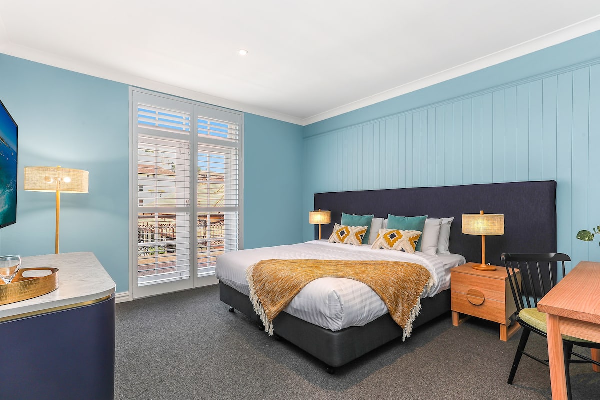 Une chambre à coucher avec un lit, des tables de chevet, un bureau et une chaise.
