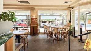 A restaurant interior with wicker chairs, a marble counter, and a view of the street outside. - Coogee Bay Hotel (Coogee)