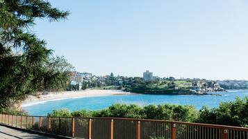 Vista costera con playa, paseo marítimo y edificios al fondo.