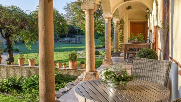 A covered outdoor area with stone columns, a round wooden table, and potted plants. - Zábřeh-Lukavice 1 by Interhome (Zabreh)