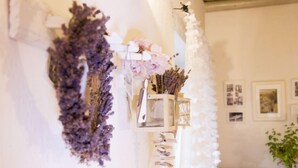 A room with a white wall adorned with dried flowers and a white garland. There are framed pictures on the wall and a small table with a plant. - Zábřeh-Lukavice 1 by Interhome (Zabreh)