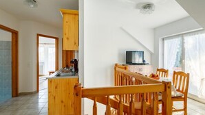Eine geräumige Küche mit Holzschränken und einem Essbereich mit Fernseher.