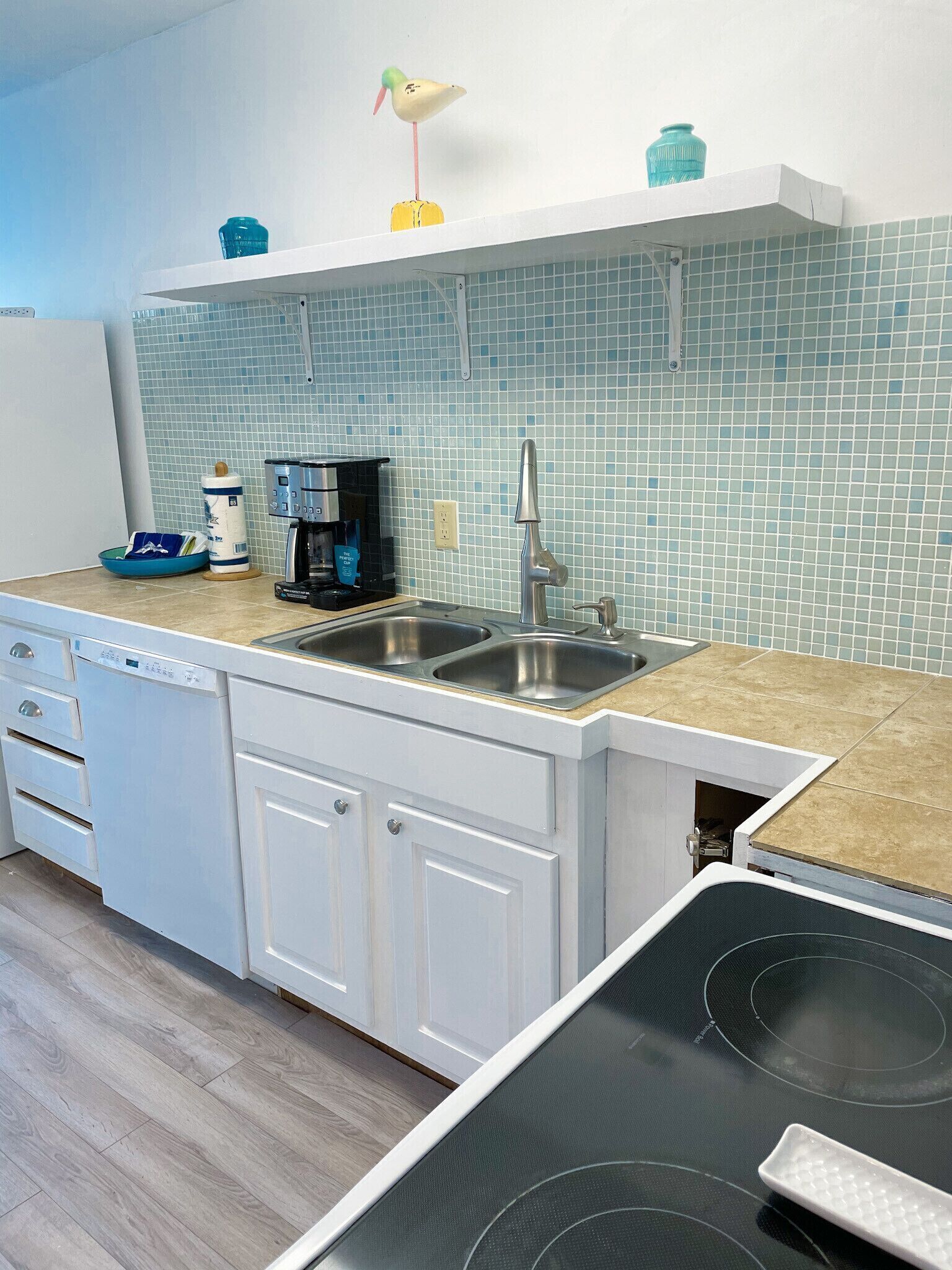 A kitchen with a double sink, white cabinets, a coffee maker, and a toaster.