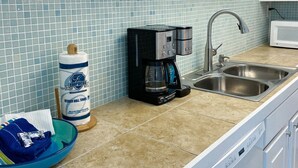 A kitchen with a coffee maker, a roll of paper towels, and a sink. - 4th floor beachfront studio with two queens (Panama City Beach)