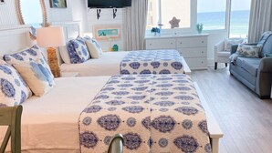 A spacious bedroom with a large bed, a TV, a desk, and a view of the sea. - 4th floor beachfront studio with two queens (Panama City Beach)