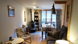 Un salon confortable avec un canapé, des fauteuils, un téléviseur et un coin repas comprenant une table et des chaises.