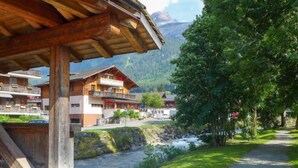 Un chalet en bois doté d’un balcon, d’un chemin de gravier et surplombant un paysage montagneux.
