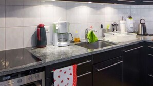 Une cuisine moderne équipée d’un four encastré, d’une machine à café et d’une bouilloire.