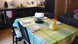 Une cuisine avec une table à manger dressée pour quatre personnes, équipée d’une machine à café, d’une bouilloire et d’un pichet jaune.
