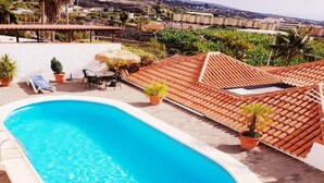 A rooftop swimming pool with a clear blue pool, surrounded by potted plants and a table with chairs. - Casa Oscar (Los Llanos de Aridane)