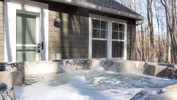 A hot tub area with a wooden deck, a door, and a window.