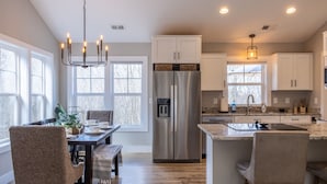 A modern kitchen with a central island, stainless steel appliances, and ample natural light from large windows. - Hot Tub, Cozy, Central Air and Heat, 5 minutes to the Ski Resort! Yes, Deer!  (Beech Mountain)