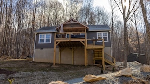 A two-story house with a wooden deck, a covered porch, and a staircase leading to the upper level. - Hot Tub, Cozy, Central Air and Heat, 5 minutes to the Ski Resort! Yes, Deer!  (Beech Mountain)