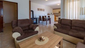 Una sala de estar con dos sofás, una mesa de centro y una zona de comedor con sillas y una mesa.