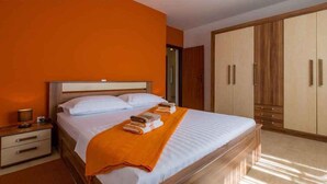 Una habitación de hotel con una cama grande, un armario de madera y una mesita de noche con lámpara.
