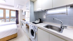 Une chambre d’hôtel moderne dotée d’un grand lit, d’une machine à laver, d’un lavabo et offrant une vue sur la ville.