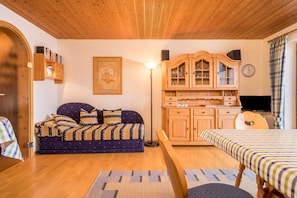 Une pièce confortable avec un canapé, un meuble en bois, une télévision et un lit.