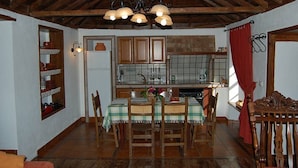 Una cocina rústica con armarios de madera, una mesa de comedor con sillas y una araña.