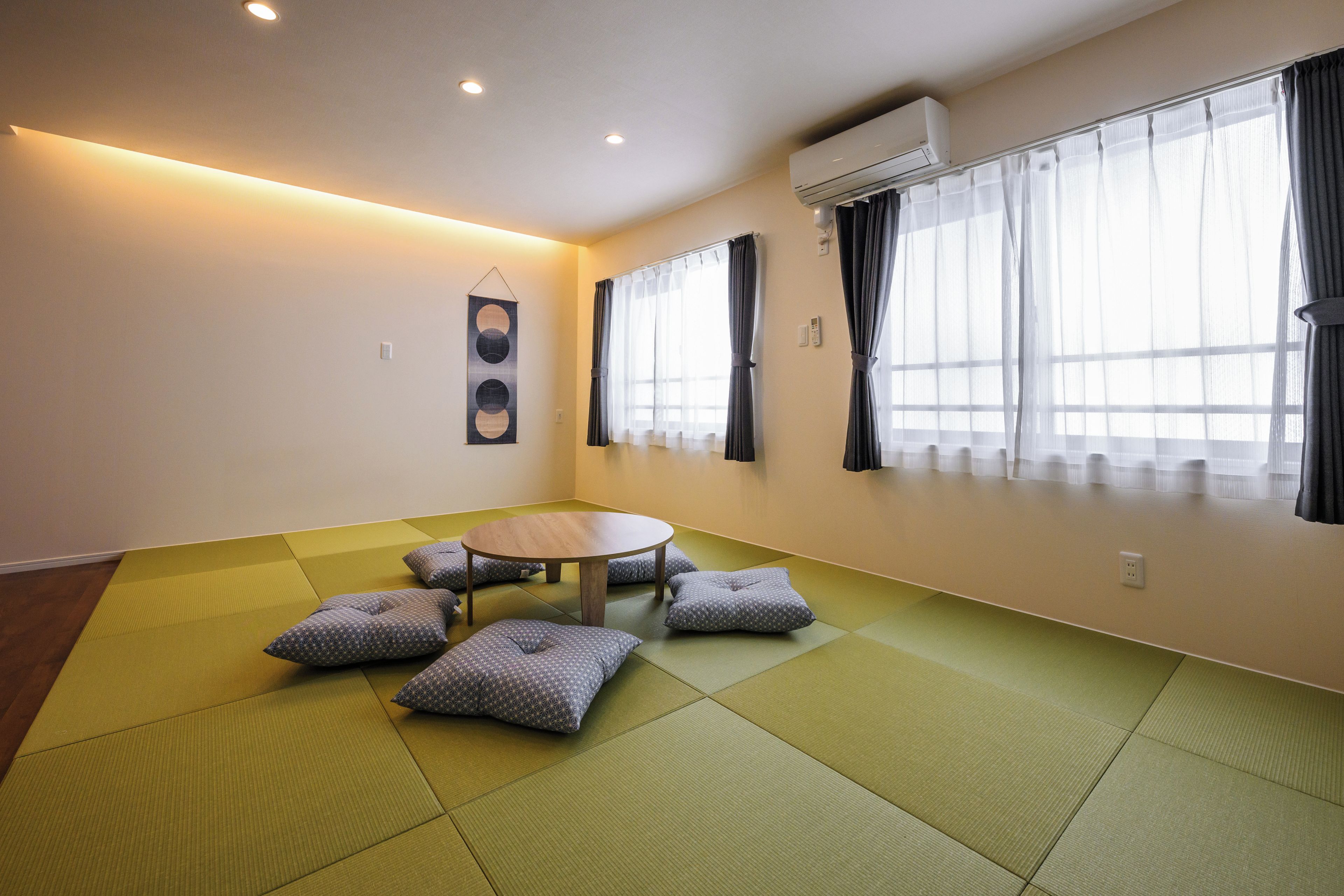 Ein Zimmer mit Tatami-Böden, einem runden Tisch und Kissen.