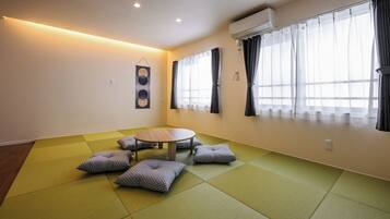 Ein Zimmer mit Tatami-Böden, einem runden Tisch und Kissen.
