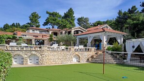 Een stenen villa met meerdere verdiepingen, een tennisbaan en een overdekt terras.