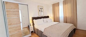Ein Schlafzimmer mit einem Bett, einem Nachttisch, einem Holzschrank und einem gerahmten Bild an der Wand.