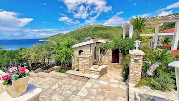 A stone pathway leading to a stone building with a view of the sea.