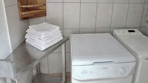 Une buanderie avec une pile de serviettes blanches, un lave-linge et une étagère en bois.