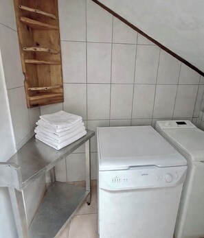 Een wasserette met een stapel witte handdoeken, een wasmachine en een houten plank.