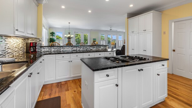 A modern kitchen with white cabinets, a central island, and a black countertop.