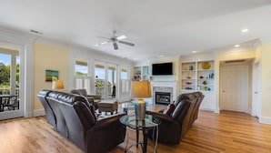 A spacious living room with leather sofas, a glass coffee table, and a fireplace.