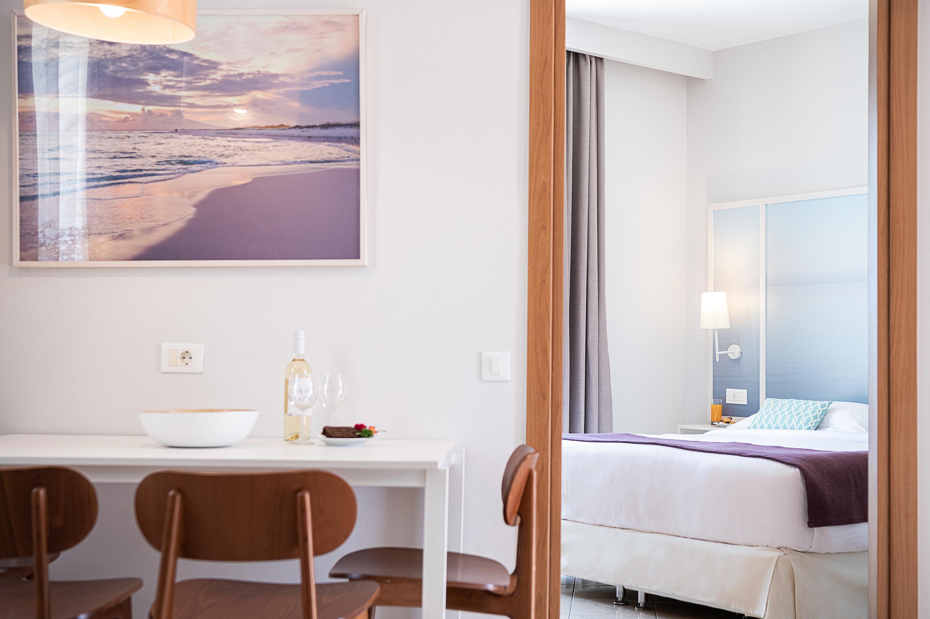 Quarto de hotel com cama, mesa de cabeceira e uma janela grande.