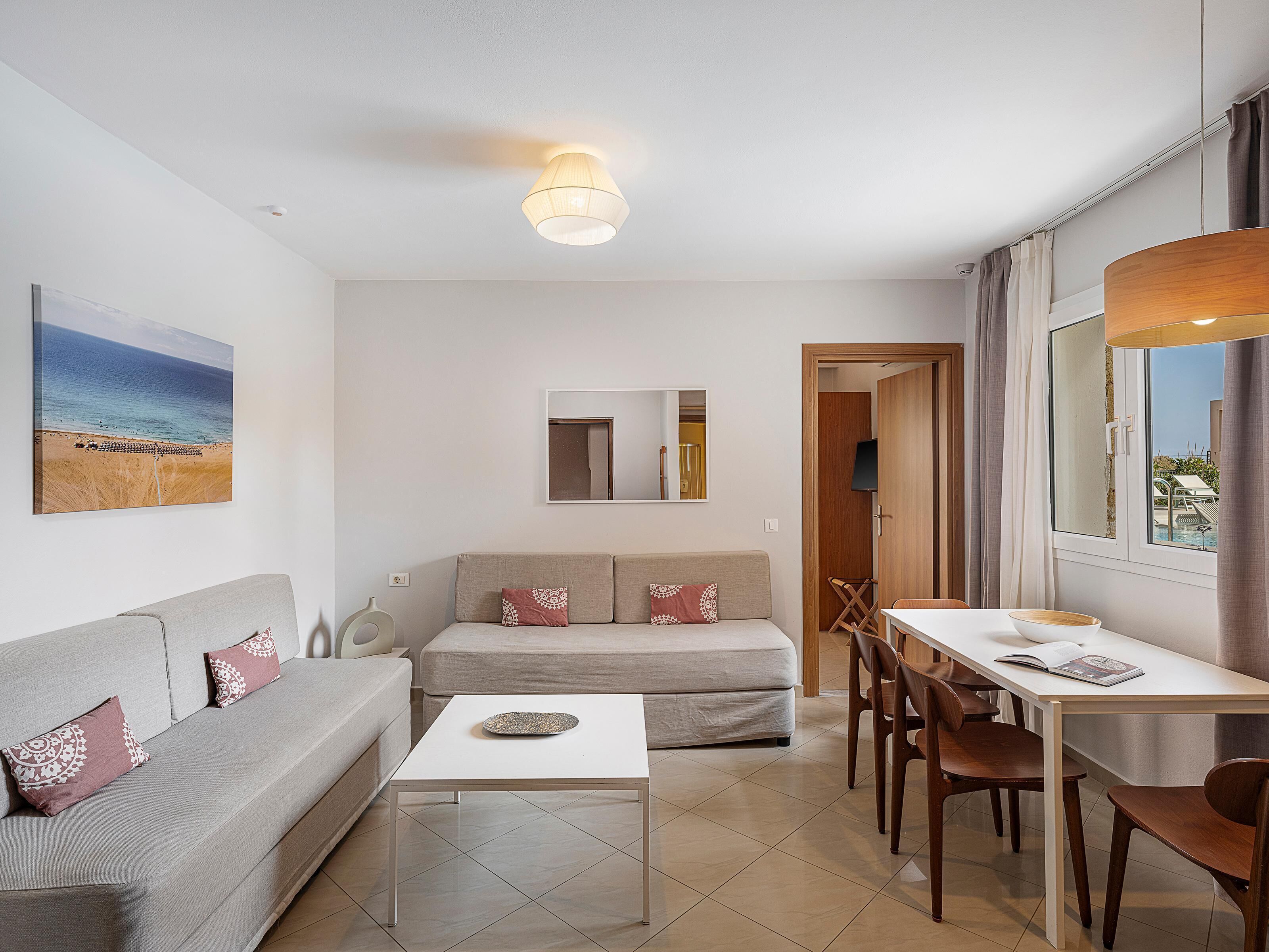 A modern living room with a sofa, a coffee table, and a dining area with chairs and a table.