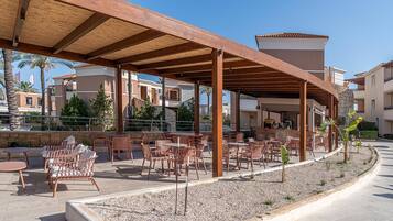 Un espace extérieur aménagé en terrasse, avec des pergolas en bois, des meubles en osier et une bordure de gravier.