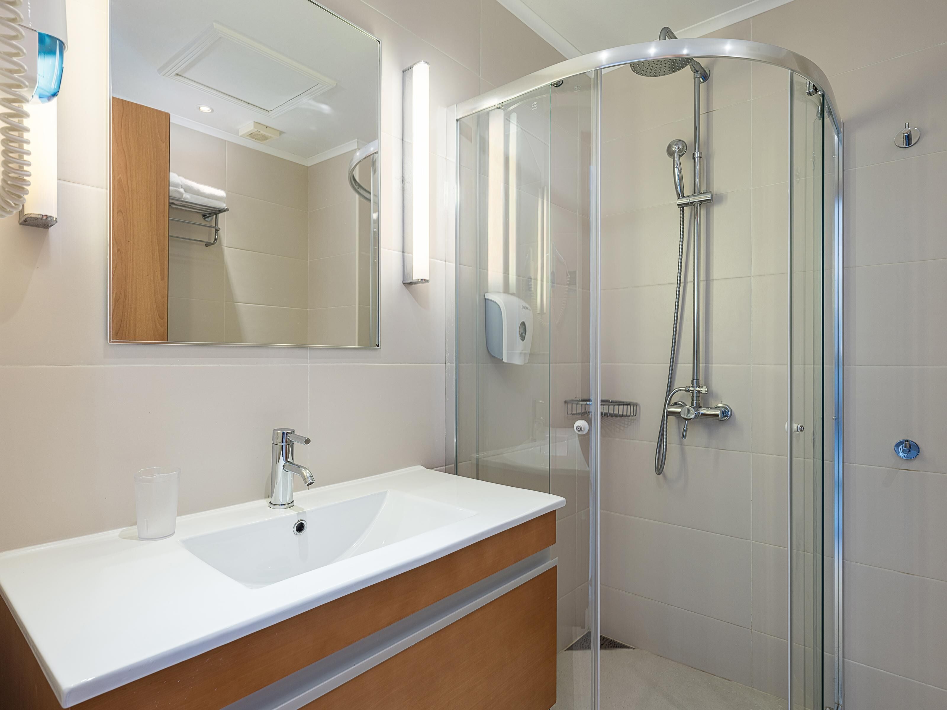 Une salle de bain moderne avec une douche à parois de verre, un lavabo blanc et un meuble-lavabo en bois.